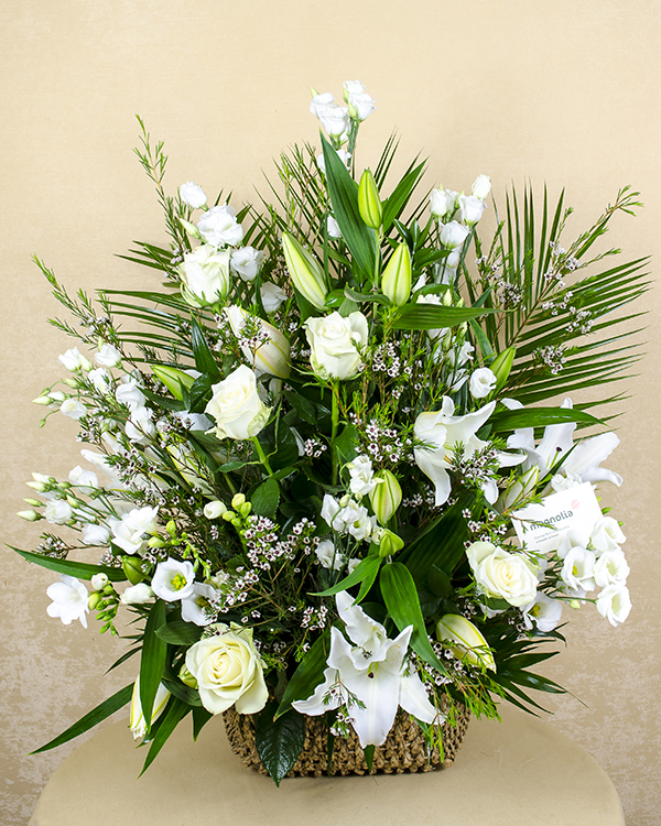 Funeral arrangement in a basket with roses, lilies and freesias