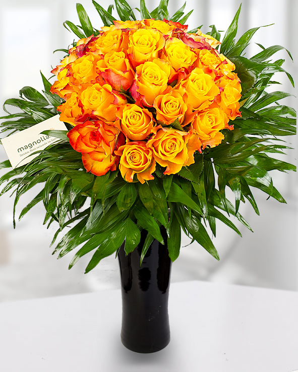 29 orange roses in a round bouquet adorned with chico