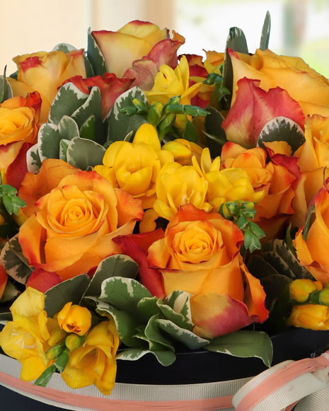 Box with freesias and orange roses