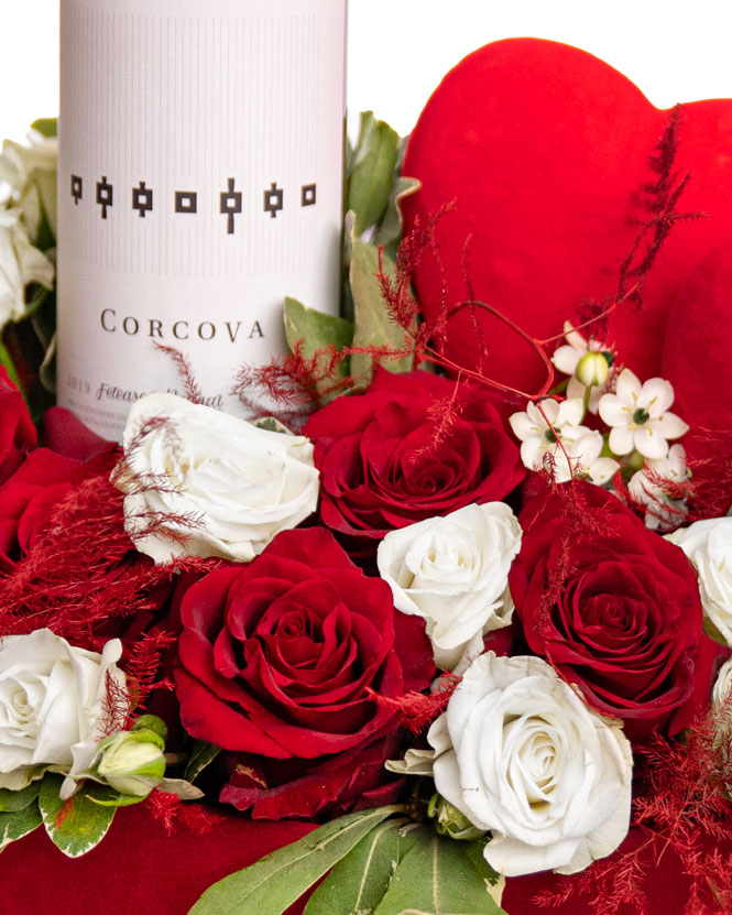 Aranjament romantic cu trandafiri și o sticlă de vin roșu