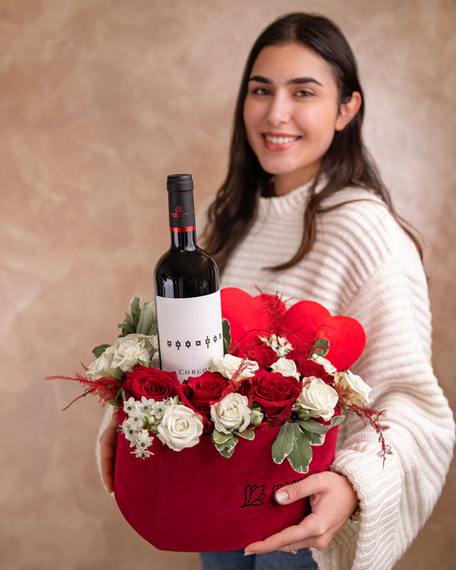 Aranjament romantic cu trandafiri și o sticlă de vin roșu