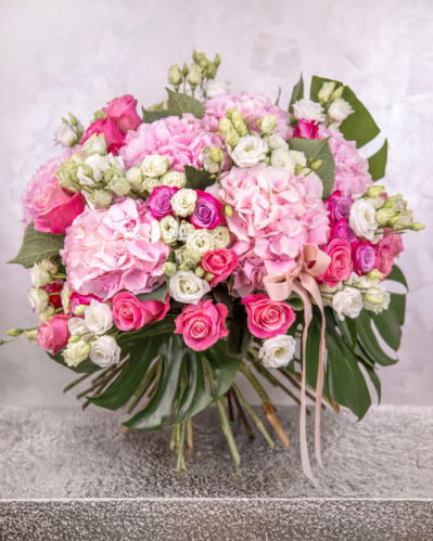 Imagine de ansamblu a buchetului de lux „Sweet Fantasy”, realizat din 10 hortensii roz, 15 trandafiri roz, 15 trandafiri mov, 11 trandafiri ramificați albi, 11 eustoma mov, 4 frunze de monstera, 15 fire de salal, completat cu 4 panglici.