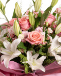 Prim-plan al florilor din buchetul "Pastel Beauty", varianta Premium, evidentiind combinatia armonioasa de 5 crini orientali albi, 6 trandafiri roz, 3 fire de lisianthus roz, 4 alstroemeria roz, completate de 4 fire de lepidium si finisate cu 2 ambalaje decorative si 2 panglici elegante.