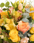 Prim-plan al florilor din buchetul “Buchet în culori calde”, varianta Premium, evidențiind combinația armonioasă de 3 Trandafiri galbeni, 4 Trandafiri portocalii, 1 fir de Alstroemeria, 2 Trandafiri ramificați galbeni și 2 fire de Lisianthus somon, completate de 1 fir de Lepidium și 1 crenguță de Eucalipt, finisate cu 1 ac decorativ cu perlă și 1 panglică neinscripționată.