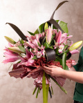 Perspectiva care evidentiaza proportiile si dimensiunea buchetului “Buchet crini orientali”, varianta Premium, o compozitie bogata alcatuita din 3 Crini orientali roz, 1 frunză de Monstera, 5 frunze de Cordiline, 4 flori de Alstroemeria, finisata elegant cu 1 element decorativ și o panglică neînscripționată.