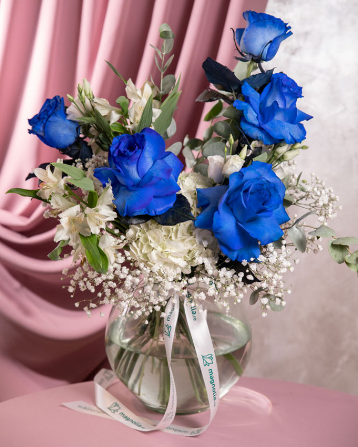 Perspectivă care evidențiază proporțiile și dimensiunea buchetului “Buchet cu Trandafiri albaștri „Blue Grace””, varianta Premium, o compoziție bogată alcătuită din 5 Trandafiri albaștri, 1 Hydrangea albă, 1 fir de Eustoma alb, 2 fire de Alstroemeria și 3 fire de Gypshopila, finisată elegant cu 1 crenguță de Eucalipt și 1 panglică Magnolia.
