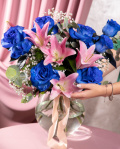 Perspectiva care evidentiaza proportiile si dimensiunea buchetului “Buchet cu Trandafiri albaștri și Crini roz „Blue Charm””, varianta Premium, o compozitie bogata alcatuita din 2 crini imperiali roz, 7 trandafiri albaștri, 2 fire de Gypsophila, 2 fire de Asparagus umbelatus și 3 crenguțe de Eucalipt, finisata elegant cu 2 panglici neînscriptionate.