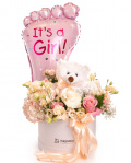 Imagine de ansamblu a aranjamentului în cutie “Aranjament floral nou-născut fetiță”, varianta Standard, realizat din o Hydrangea albă, o Hydrangea light pink, 3 Trandafiri albi, 4 Trandafiri roz, 2 Trandafiri ramificați roz, 2 flori de Eustoma somon, o crenguță de Gypsophila, completat cu 2 crenguțe de Asparagus umbelatus, o crenguță de Pittosporum ilan, un ursuleț mic alb, o perlă decorativă cu ac și 2 panglici neinscripționate.