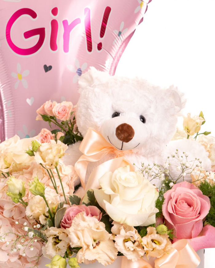 Prim-plan al florilor din aranjamentul în cutie “Aranjament floral nou-născut fetiță”, varianta Standard, evidențiind combinația armonioasă de o Hydrangea albă, o Hydrangea light pink, 3 Trandafiri albi, 4 Trandafiri roz, 2 Trandafiri ramificați roz și 2 flori de Eustoma somon, completate de Gypsophila, Asparagus umbelatus și Pittosporum ilan, finisate cu un ursuleț mic alb și 2 panglici neinscripționate elegante.