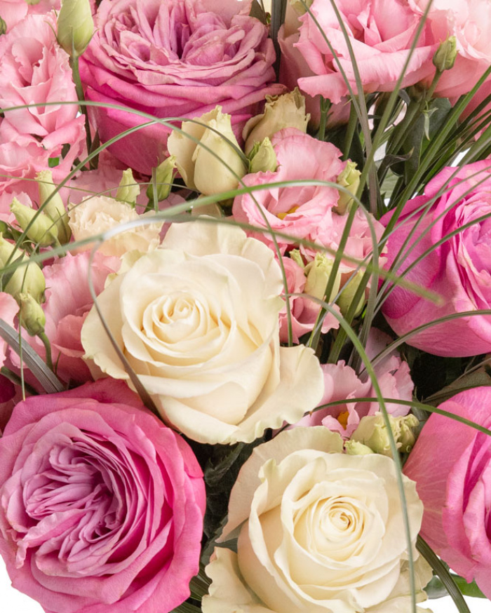 Prim-plan al florilor din buchetul “Buchet cu trandafiri mov și lisianthus”, varianta Premium, evidențiind combinația armonioasă de 5 Trandafiri albi, 6 Eustoma roz, 5 Trandafiri mov, completate de 15 fire de Beargrass și finisate cu 2 panglici inscripționate elegante.