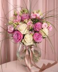 Perspectivă care evidențiază proporțiile și dimensiunea buchetului “Buchet cu trandafiri mov și lisianthus”, varianta Premium, o compoziție bogată alcătuită din 5 Trandafiri albi, 6 Eustoma roz, 15 fire de Beargrass și 5 Trandafiri mov, finisată elegant cu 2 panglici inscripționate.