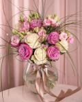 Perspectivă care evidențiază proporțiile și dimensiunea buchetului “Buchet cu trandafiri mov și lisianthus”, varianta Premium, o compoziție bogată alcătuită din 5 Trandafiri albi, 6 Eustoma roz, 15 fire de Beargrass și 5 Trandafiri mov, finisată elegant cu 2 panglici inscripționate.