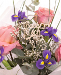 Prim-plan al florilor din buchetul “Buchet trandafiri roz și iriși „Back to school"”, varianta Premium, evidențiind combinația armonioasă de 5 Trandafiri roz și 6 Iriși, completate de Gypsophila, Eucalipt, Beargrass și finisate cu topper tematic, ambalaj și o panglică elegantă.