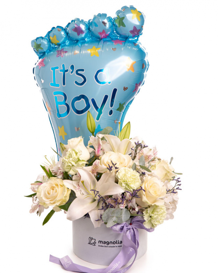 Imagine de ansamblu a aranjamentului “Aranjament floral „It'a a Boy””, varianta Premium, realizat din 7 Trandafiri albi Mondial, 2 Crini imperiali albi, 4 Garoafe verzi, 3 Alstroemeria, 1 fir de Limonium, 2 crenguțe de Eucalipt, completat cu un balon festiv It's a Boy, 1 perlă pe ac, cutie Magnolia și panglică personalizată.