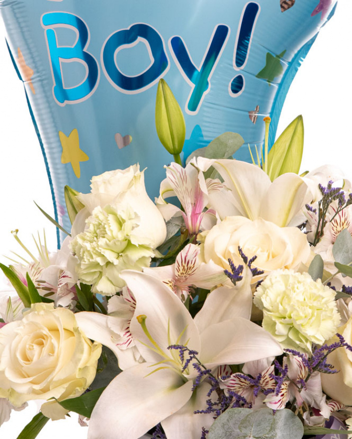 Prim-plan al florilor din aranjamentul “Aranjament floral „It'a a Boy””, varianta Premium, evidentiind combinatia armonioasa de 7 Trandafiri albi Mondial, 2 Crini imperiali albi, 4 Garoafe verzi, 3 Alstroemeria, 1 fir de Limonium, completate de 2 crenguțe de Eucalipt si finisate cu un balon festiv albastru, 1 perlă pe ac, cutie Magnolia și panglici elegante.