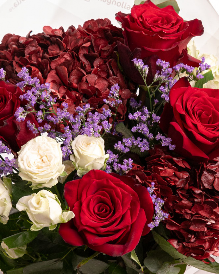 Prim-plan al florilor din buchetul “Buchet cu Trandafiri și Hortensii”, varianta Premium, evidentiind combinatia armonioasa de 5 Trandafiri Freedom, 2 Hortensii bordo, 2 Trandafiri ramificați albi, 1 fir de Limonium, completate de 2 crenguțe de Eucalipt si finisate cu ambalaj decorativ și panglică Magnolia elegante.