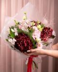 Perspectiva care evidentiaza proportiile si dimensiunea buchetului “Buchet cu Hortensii „Fall Elegance””, varianta Premium, o compozitie bogata alcatuita din 3 Hydrangea bordo, 2 Eustoma roz, 2 Alstroemeria, 4 fire de Asparagus umbelatus, 2 fire de Stypha, finisata elegant cu 1 ambalaj decorativ și 1 panglică inscripționată Magnolia.