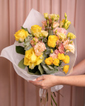 Perspectiva care evidentiaza proportiile si dimensiunea buchetului “Buchet Trandafiri şi Eustoma”, varianta Premium, o compozitie bogata alcatuita din 7 Trandafiri galbeni, 3 fire de Eustoma somon, 1 fir de Trandafir ramificat galben și 2 crenguțe de Eucalipt, finisata elegant cu ambalaj decorativ și o panglică.