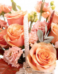 Prim-plan al florilor din coșul “Coș cu trandafiri portocalii și eustoma”, varianta Premium, evidentiind combinatia armonioasa de 6 Trandafiri portocalii, 2 Eustoma somon, completate de 1 ramură de Quercus, 1 fir de Asparagus cupru, 2 crenguțe de Eucalipt si finisate cu 1 coș alb împletit și 1 șirag de mărgele elegante.