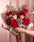 Perspectiva care evidentiaza proportiile si dimensiunea buchetului “Buchet cu trandafiri roșii „Rose Whisper””, varianta Premium, o compozitie bogata alcatuita din 7 Trandafiri roșii, 3 Trandafiri ramificați roz, 3 fire de Chamelaucium roz, 2 fire de Symphoricarpos și 3 crenguțe de Eucalipt, finisata elegant cu 2 ambalaje decorative și o panglică Magnolia.