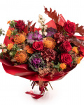 Imagine de ansamblu a buchetului “Buchet de toamnă „Exotic Love””, varianta Premium, realizat din 5 Trandafiri roșii, 3 Leucospermum, 3 Brassica, 3 Carthamus, 2 Hydrangea burgundy, 1 Trandafir ramificat portocaliu, 2 Symphoricarpos, 3 fire de Asparagus cupru și 3 crenguțe de Quercus, completat cu ambalaj decorativ și o panglică Magnolia.