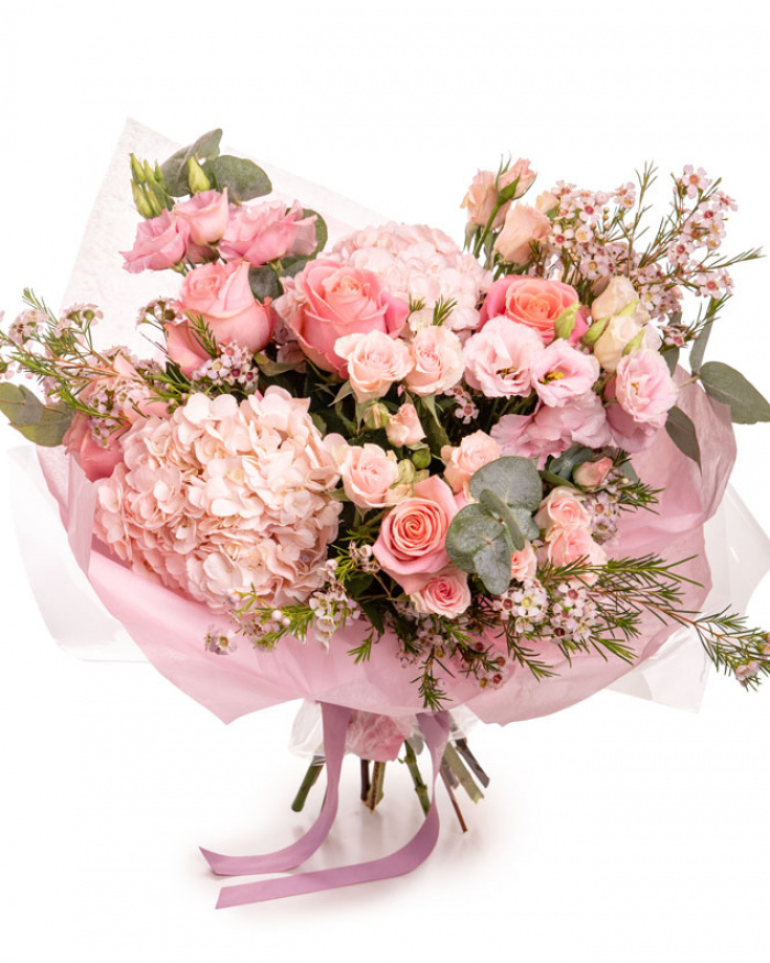 Imagine de ansamblu a buchetului “Buchet luxuriant cu flori roz”, varianta Premium, realizat din 2 Hortensii roz, 5 Trandafiri roz, 4 Trandafiri ramificați roz, 4 fire de Chamelaucium roz, 2 fire de Eustoma roz și 3 crenguțe de Eucalipt, completat cu 2 ambalaje decorative și o panglică Magnolia.
