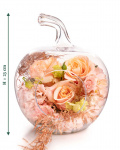 Imagine de ansamblu a aranjamentului “Aranjament floral „Peach Glow””, varianta Standard, realizat din 3 Trandafiri portocalii, 1 Hydrangea roz, 1 Eustoma somon, completat cu 1 crenguță de Asparagus coloured, 1 crenguță de Eucalipt și prezentat într-un vas din sticlă în formă de măr.
