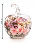 Imagine de ansamblu a aranjamentului floral “Aranjament floral „Blush Apple””, varianta Standard, realizat dintr-un fir de Trandafir ramificat roz, o crenguță de Chamelaucium roz, o crenguță de Symphoricarpos, o crenguță de Eucalipt și un fir de Asparagus colorat, completat cu un vas din sticlă în formă de măr.